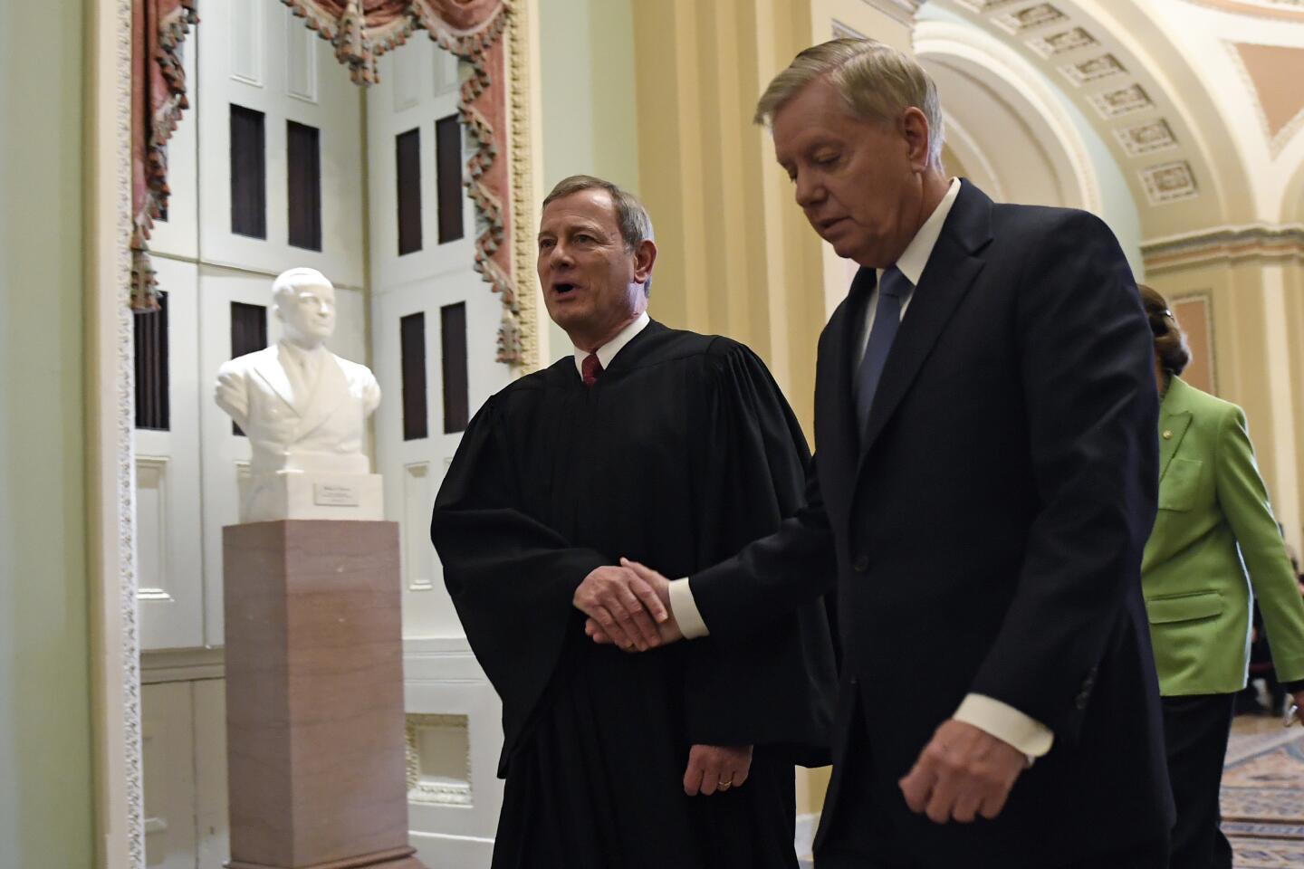 Sen. Lindsey Graham (R-S.C.) shakes hands with Supreme Court Chief Justice John G. Roberts Jr. as they leave Senate chambers.