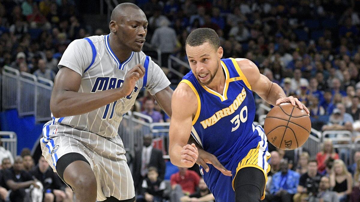 Warriors guard Stephen Curry (30) drives to the basket against Magic center Bismack Biyombo (11) during the first half Sunday.