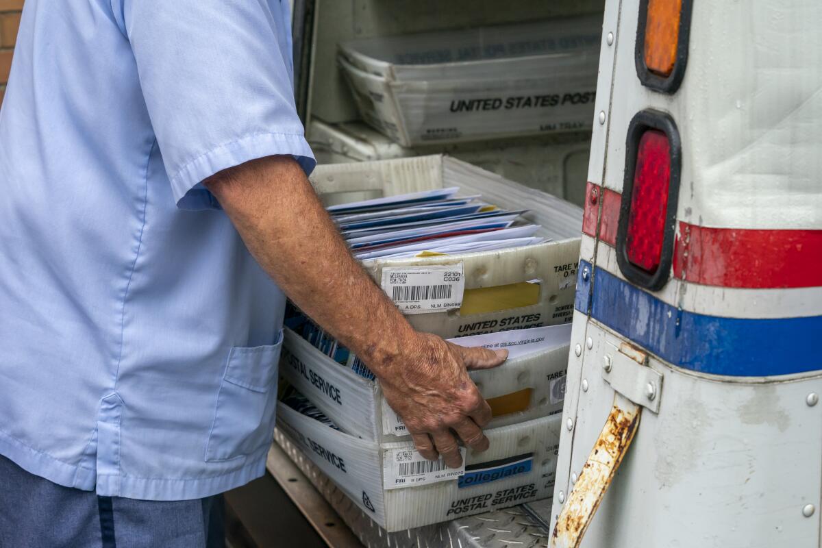 Letter carriers load mail trucks for deliveries at a U.S. Postal Service facility in McLean, Va. 