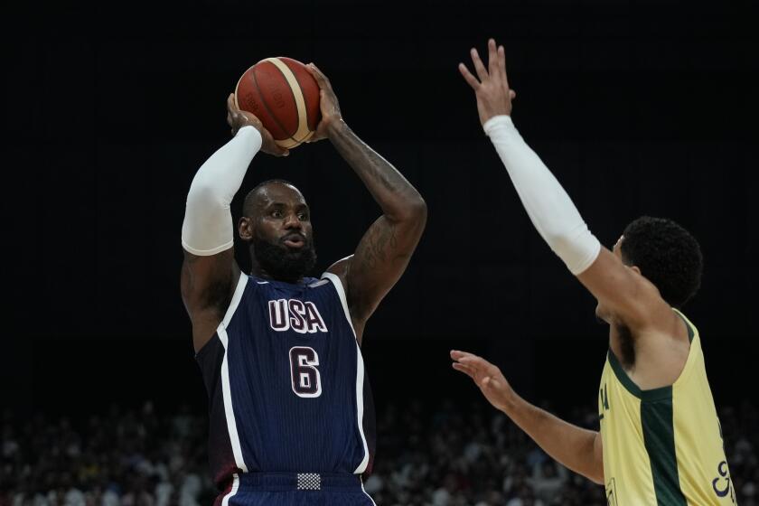 El estadounidense LeBron James, a la izquierda, busca disparar mientras el australiano Josh Green, a la derecha, intenta bloquear durante el USA Basketball Showcase en Abu Dhabi, Emiratos Árabes Unidos, el lunes 15 de julio de 2024. (AP Foto/Altaf Qadri)