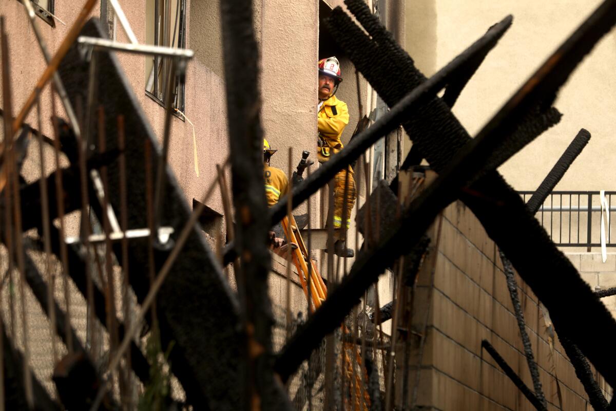 Firefighters hit hot spots at a fire-damaged apartment building.
