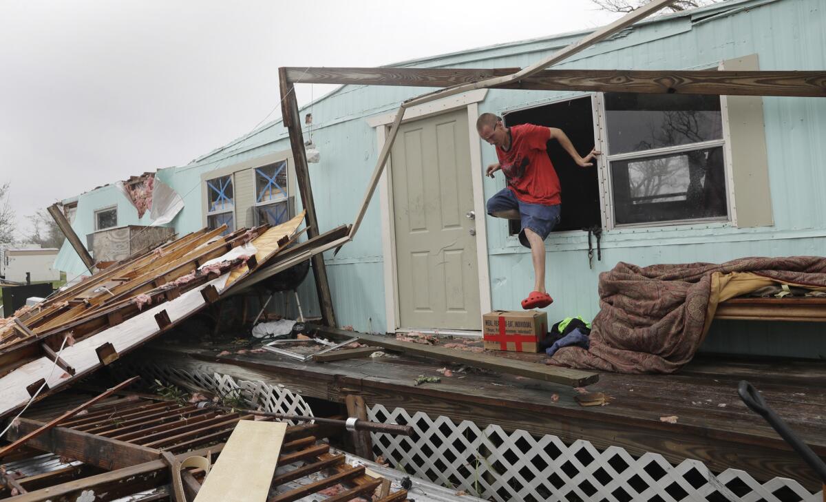 Sam Speights exits a window of his home that was destroyed in the wake of Hurricane Harvey in Rockport, Texas.