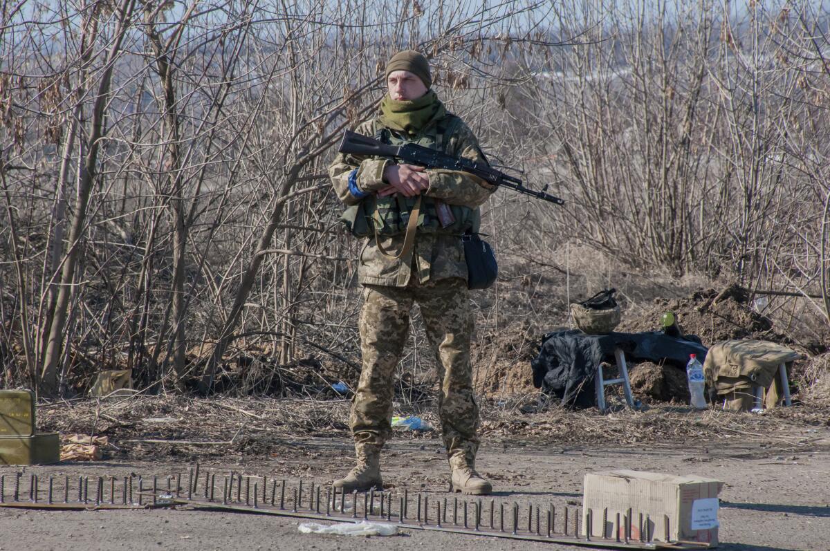 A Ukrainian soldier stands outside with a gun.