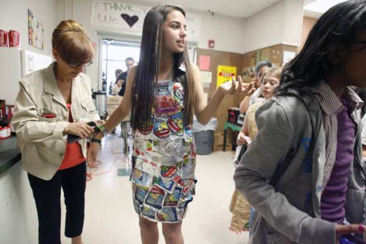 Mona Bitar, 13, middle, wears a Capri Sun dress while Mary Monsaour , left, helps Bitar with her bracelet during the Trashin' Fashion event, which took place at John Muir Middle School in Burbank on Friday. Eighth graders are fundraising for their eighth grade party and are trying to raise at least $2,000.