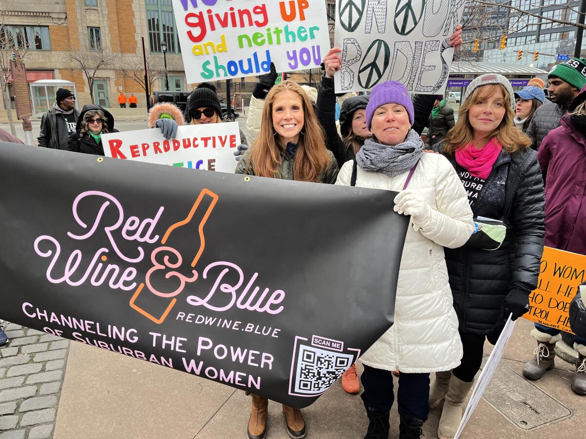 Three women hold a banner at a march in Cleveland