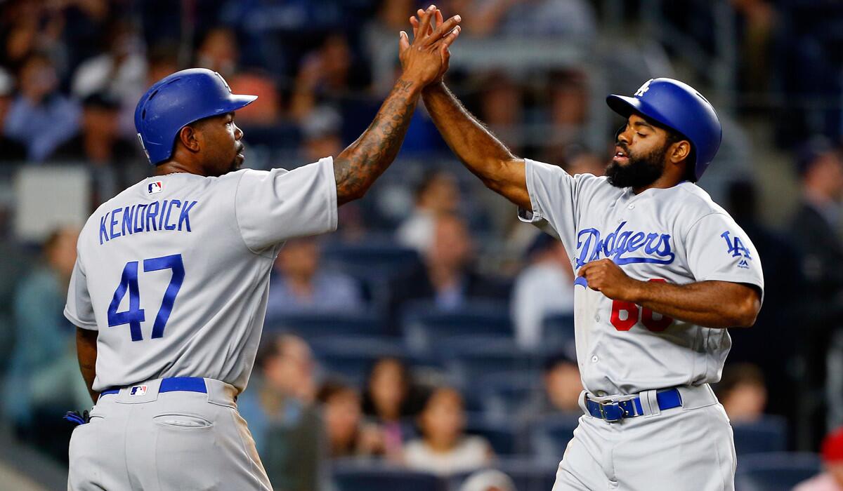 Dodgers' Andrew Toles, right, and Howie Kendrick high-five after scoring in the second inning against the New York Yankees on Sept. 12.