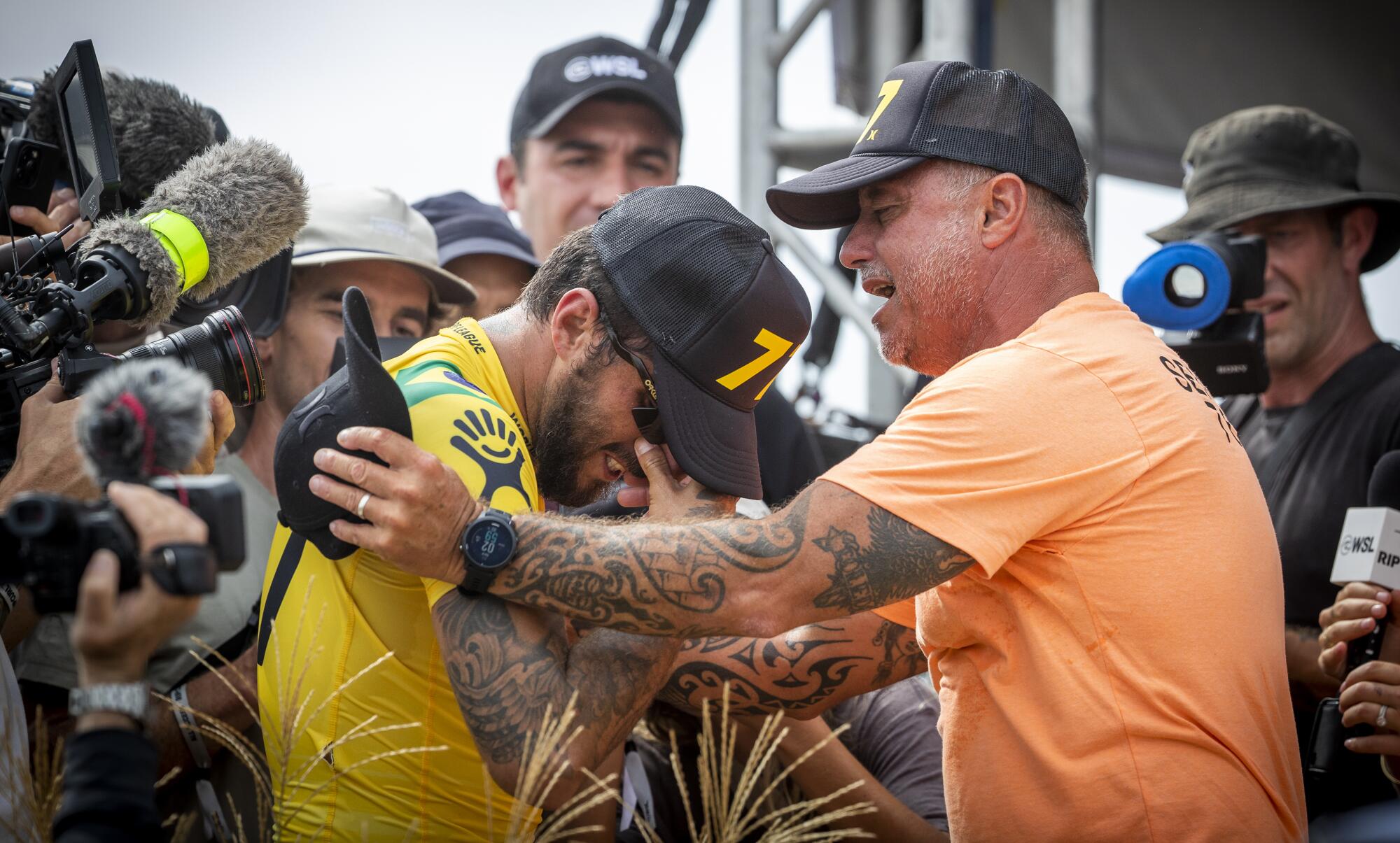 Filipe Toledo wipes away tears while getting a hug from his father, Ricardo, after winning the world title.