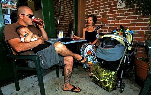On Anacapa Brewing Co.'s front patio, Matt Lyon and wife Dustin Lyon relax, with Matt taking a sip of Pale Ale while holding 6-month-old son Ryder.