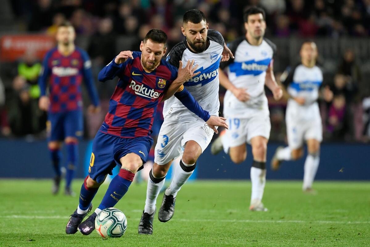 Barcelona forward Lionel Messi, left, vies for the ball with Alaves defender Ruben Duarte