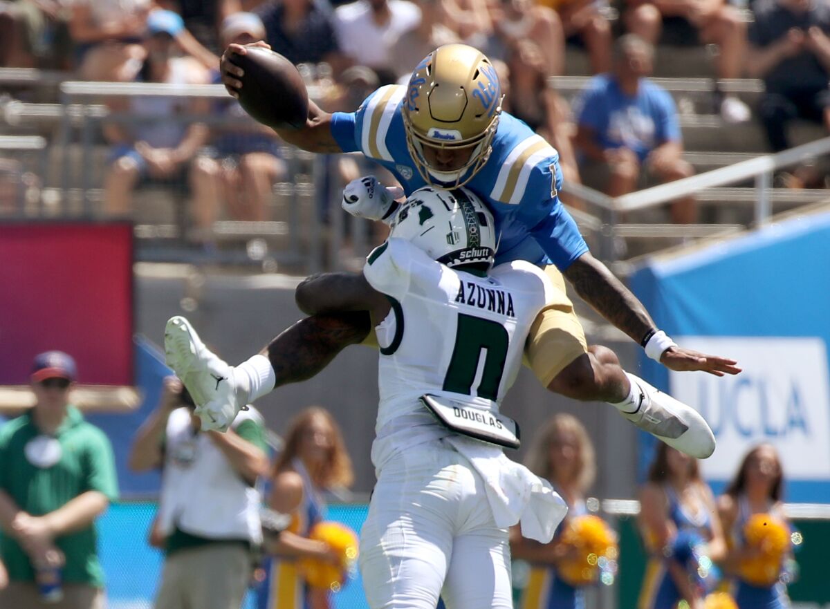 UCLA quarterback Dorian Thompson-Robinson tries to hurdle over Hawaii defender Chima Azonnah.