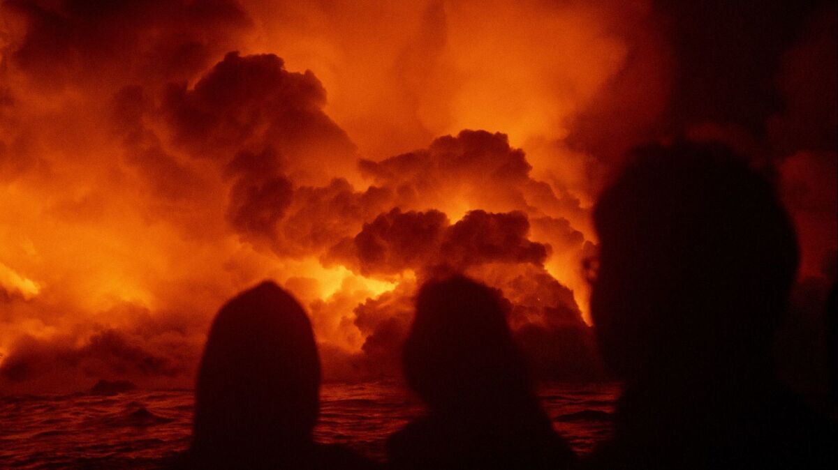 People aboard Lava Ocean Tours' boat the Hot Shot watch as lava flows into the ocean near Pahoa, Hawaii, on July 2.