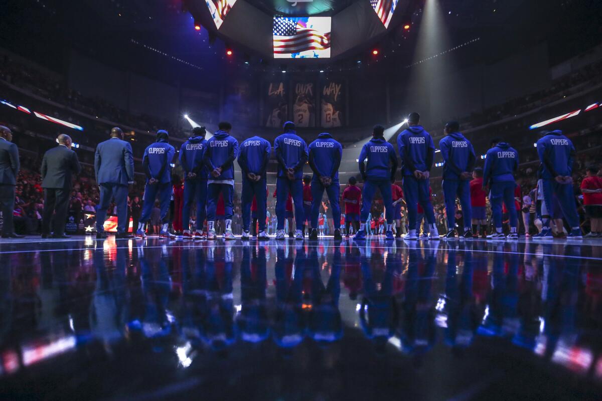 The Clippers and the Charlotte Hornets stand during the national anthem prior to the Clippers' 111-96 win at Staples Center on Monday.