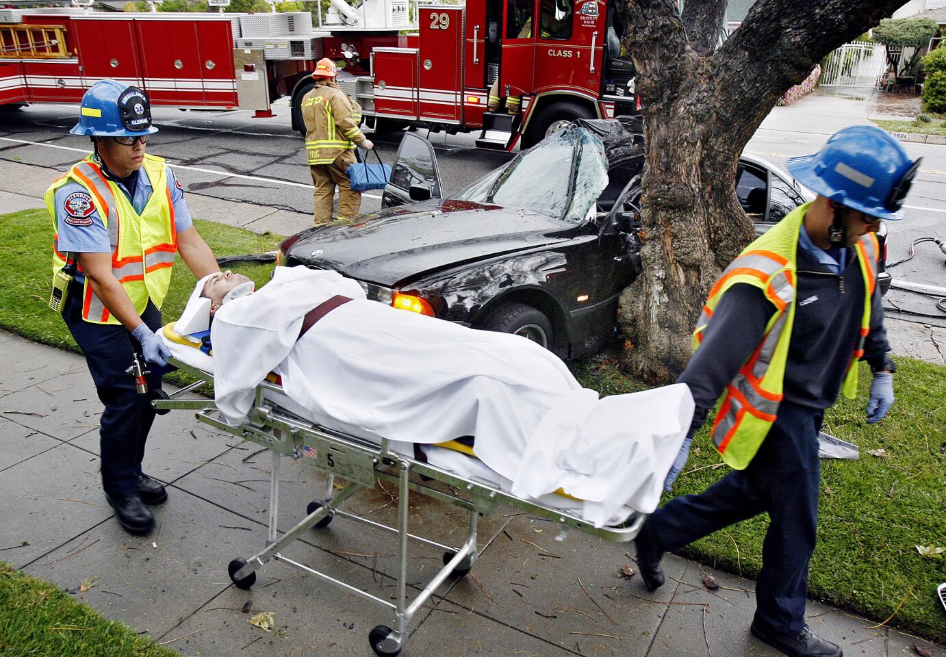 The driver of a wrecked vehicle in the background is taken to an ambulance on Friday, April 13, 2012.