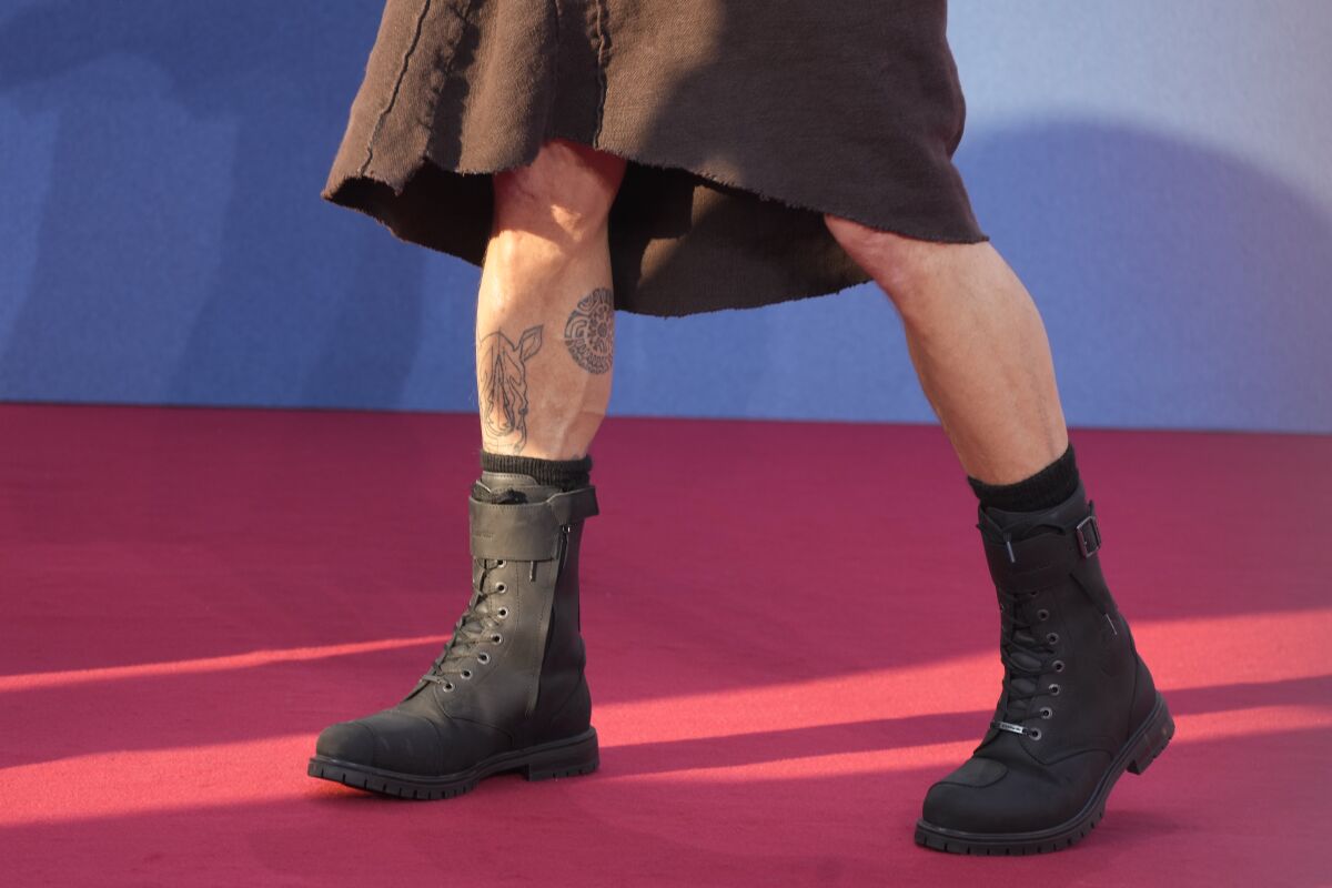 Brad Pitt's legs are shown in heavy boots as he wears a skirt to the "Bullet Train" premiere