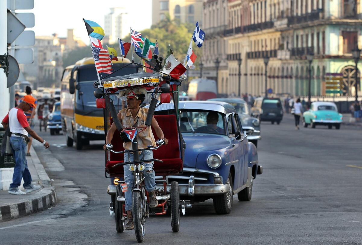Un bicitaxi adornado con varias banderas, entre ellas una de EE.UU., circula por una calle de La Habana, la capital cubana.