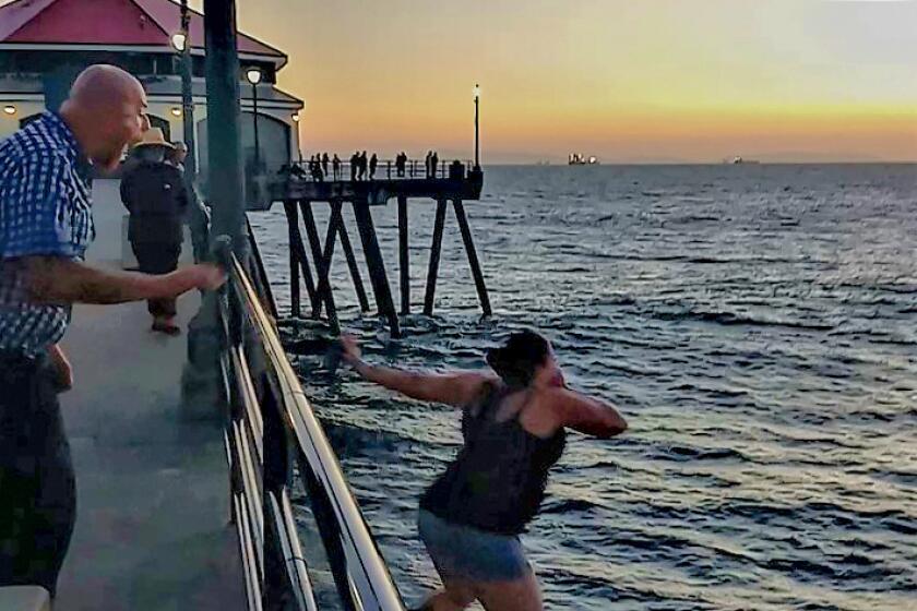 A man identified as Fenton Dee III, of Norwalk, left, shouts at a woman in his company as she jumps off the Huntington Beach Pier Sunday. Dee later jumped after her and was declared dead.