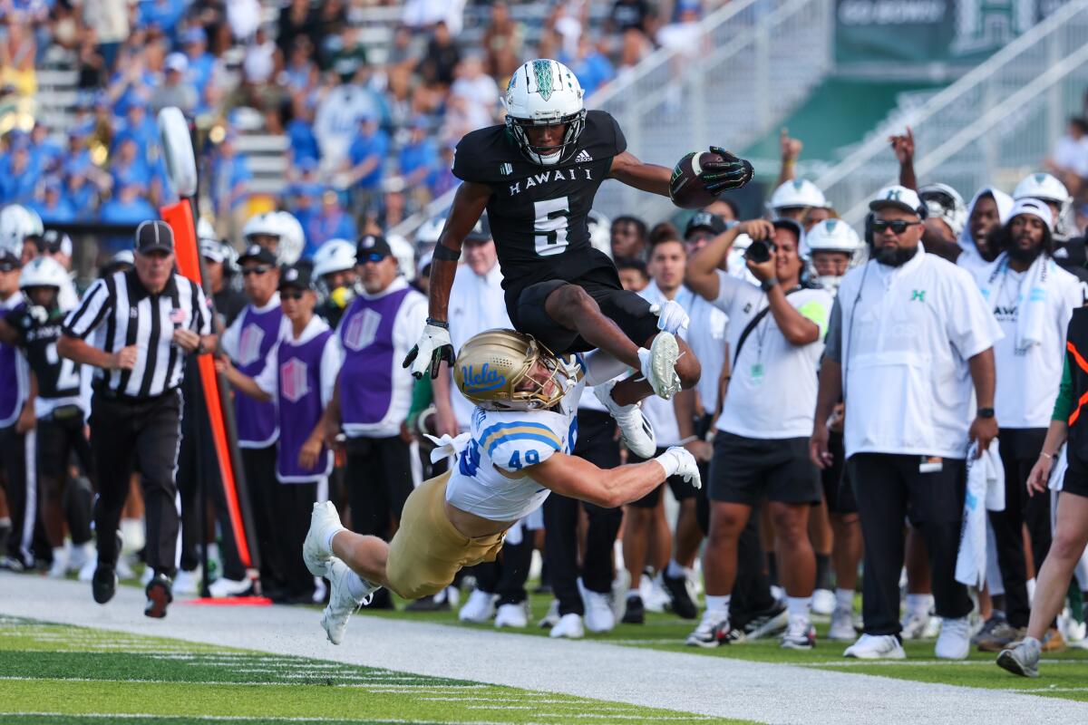 Hawaii's Pofele Ashlock carries the ball and leaps over UCLA's Carson Schwesinger during the Bruins' win 