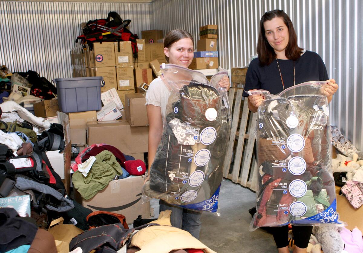 Sarah Johnson, 25, from Littlefield, Texas, left, and Glendale resident Cristal Logothetis, 31, founder of CarryTheFuture.org, show some of the 1,700 baby carriers they have collected and are ready to distribute in Greece. Logothetis is taking four suitcases full of baby carriers to donate to Syrian refugees that arrive at the islands of Greece.