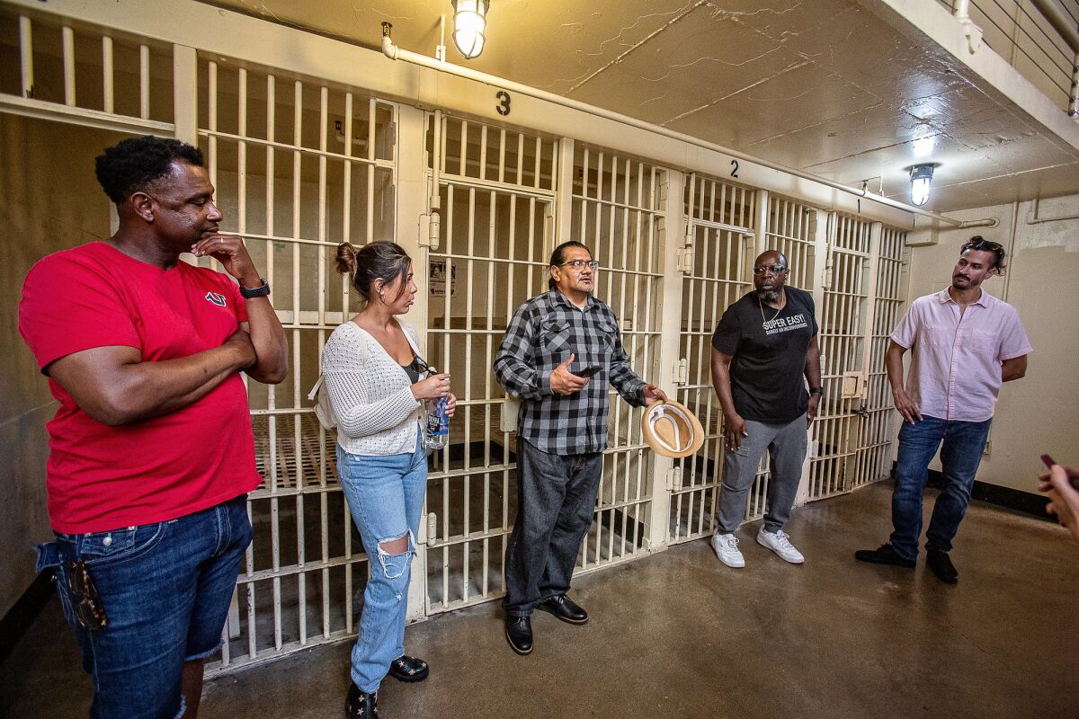 Five people stand outside an old jail cell in San Diego.