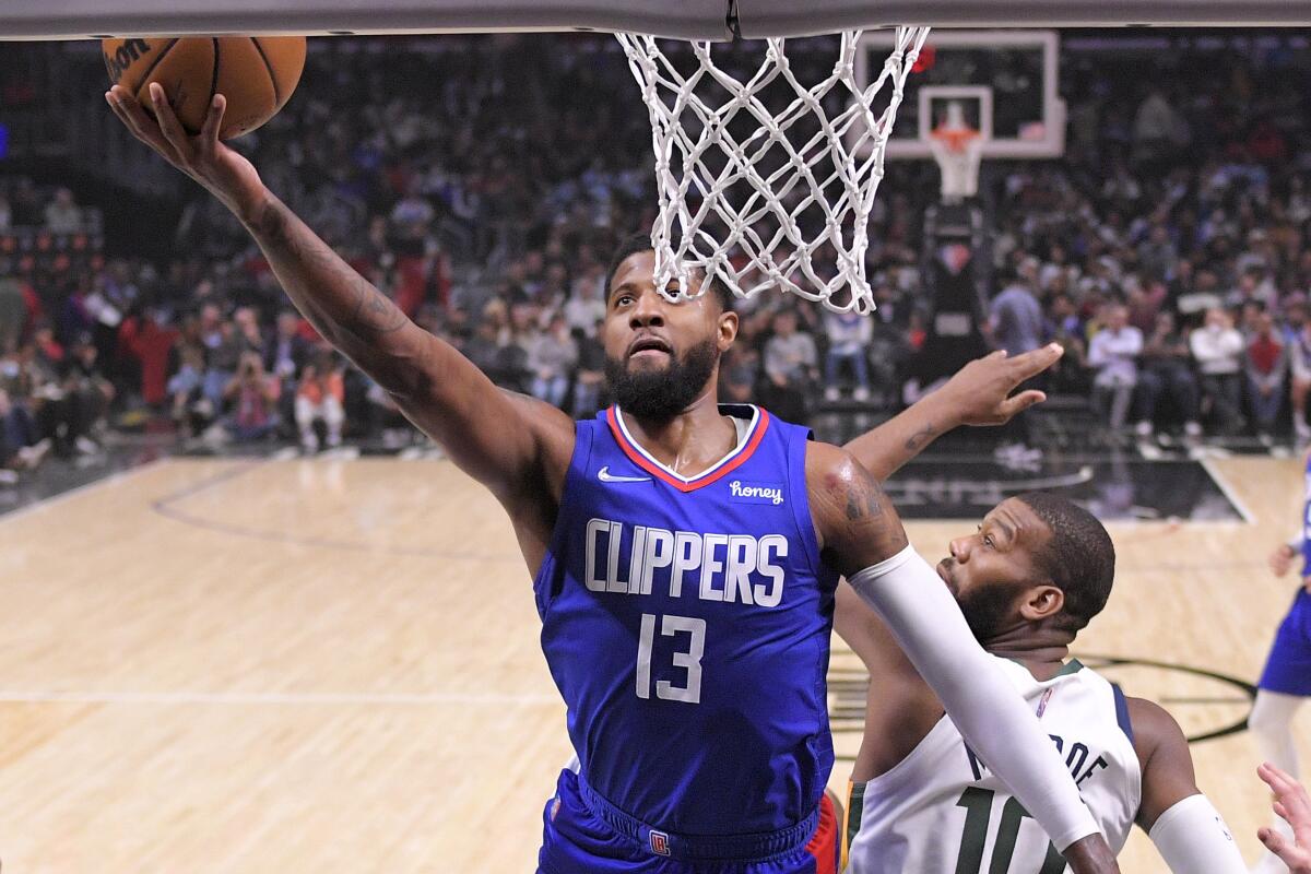 Clippers guard Paul George, left, shoots as Utah Jazz center Greg Monroe defends 