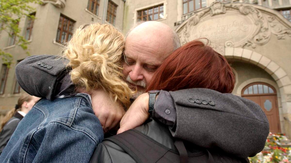 Teacher Rainer Heise hugs two students in front of the Gutenberg school in Erfurt, Germany, on April 29, 2002, three days after a 19-year-old gunman killed 16 people and then himself at the school.