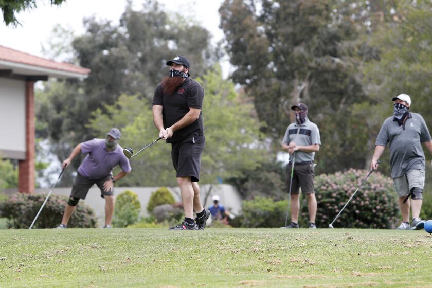 Golfer Eddie Rodriguez, 30, tees off as he begins a round of golf with, from left to right, Nick Pederson, 29, brother Justin Rodriguez, 29, and Todd Carbello, 58, at Costa Mesa Country Club on Wednesday, April 29. The city of Costa Mesa has begun to slowly lighten up the stay-at-home rules allowing for golf courses, biking and walking trials to reopen.
