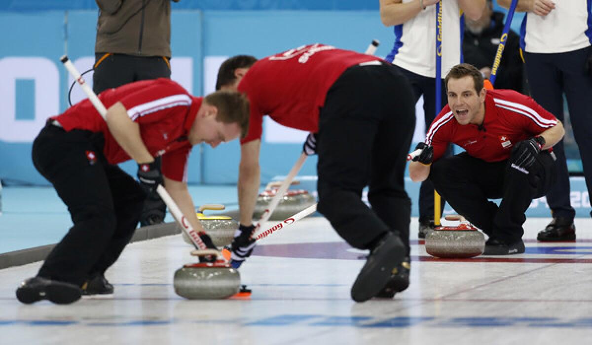 Switzerland's skip Sven Michel, right, shouts instructions from the house to sweepers Simon Gempeler, left, and Sandro Trolliet during an Olympics match against Sweden on Monday.