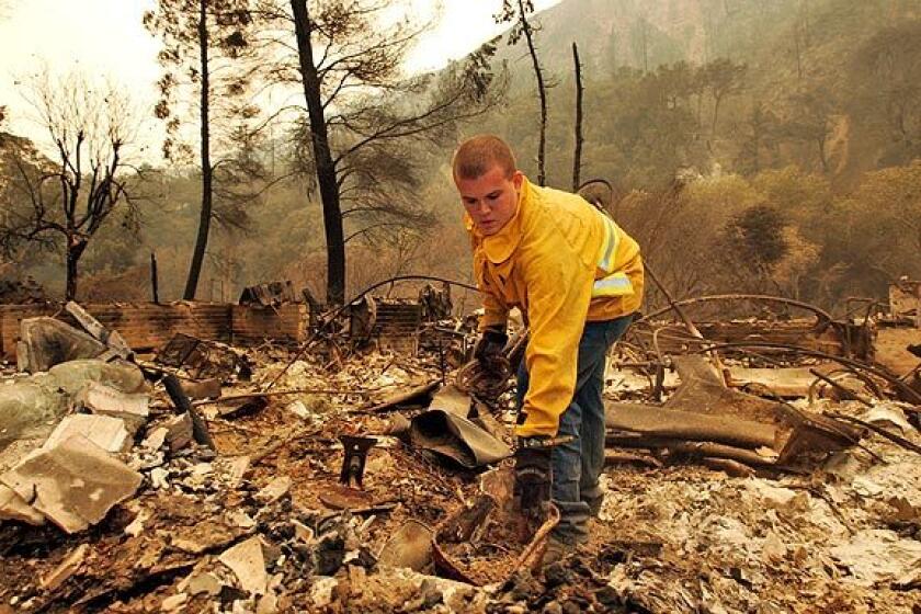 Travis Riner, 25, tries to salvage whatever he can from the charred remains of the home where he had lived for eight years on the 3000 block of Stonyvale Road at Vogel Flat in Tujunga.