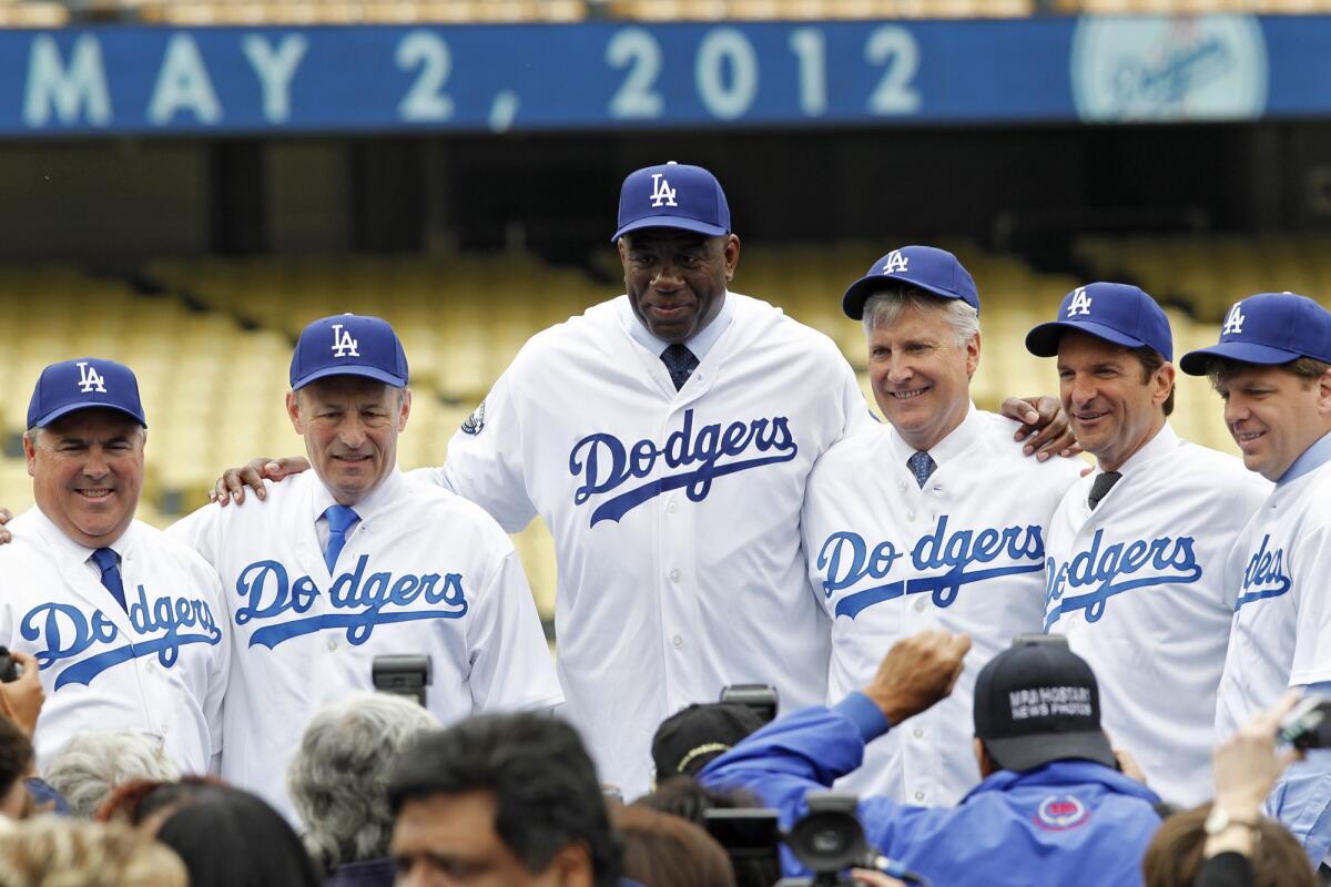 Dodgers owners, including Lakers legend Magic Johnson, center, pose for photos.