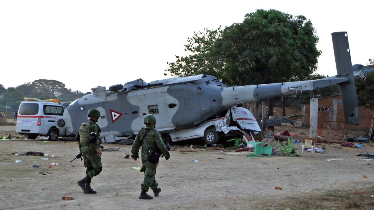 Mexican soldiers walk near the wreckage of a military helicopter that crashed Friday in southern Mexico.