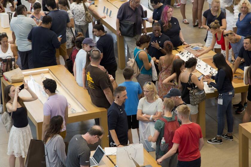 Customers browse in an Apple store, Thursday, Aug. 2, 2018, in New York. Apple has become the world's first publicly traded company to be valued at $1 trillion. The milestone marks the triumph of stylish technology that has redefined what we expect from our gadgets ever since two mavericks named Steve started the company 42 years ago. (AP Photo/Mark Lennihan)