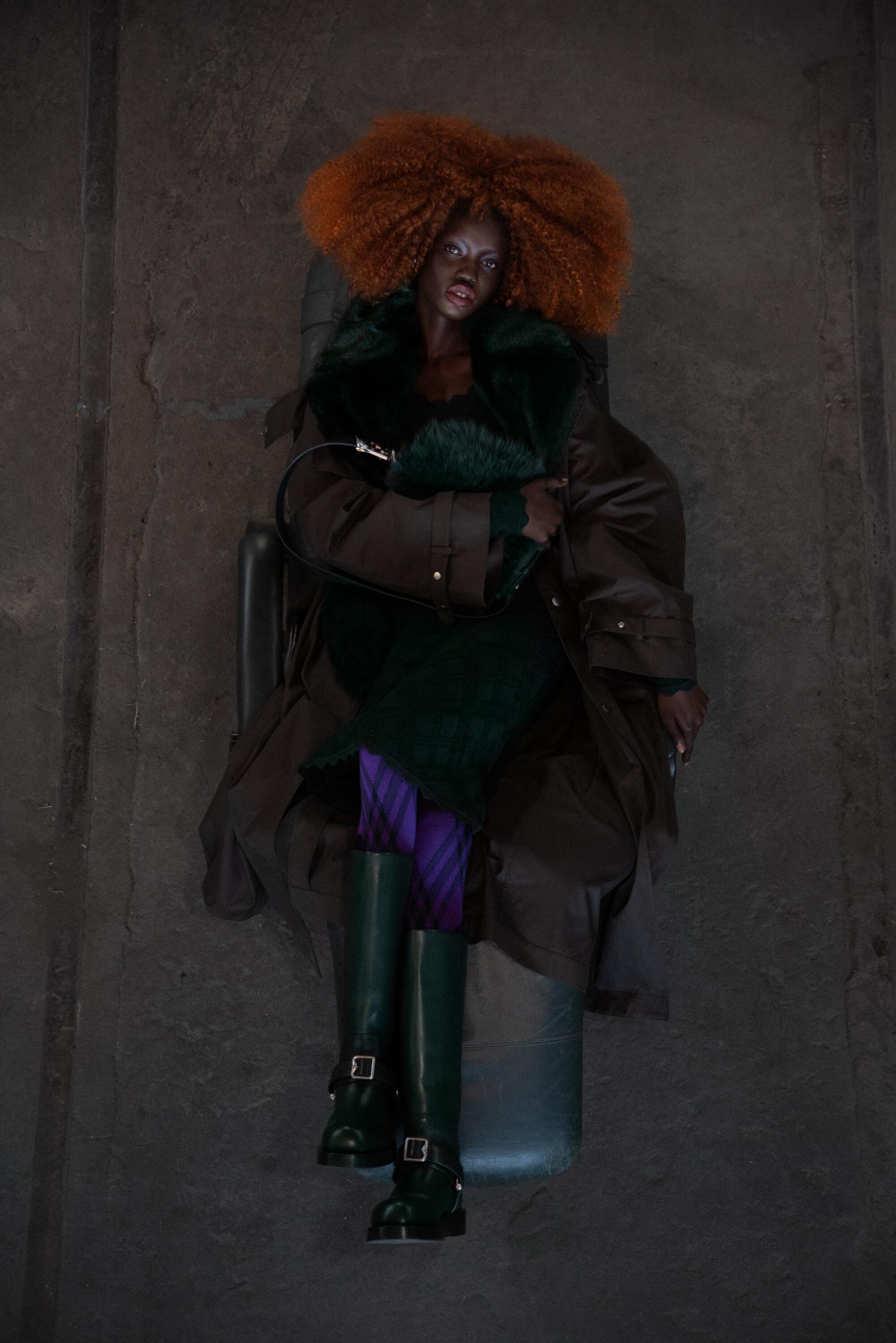 Model Aker Ajak wears Burberry Gabardine faux fur trench coat, Aran wool blend dress, leather and shearling small Knight bag