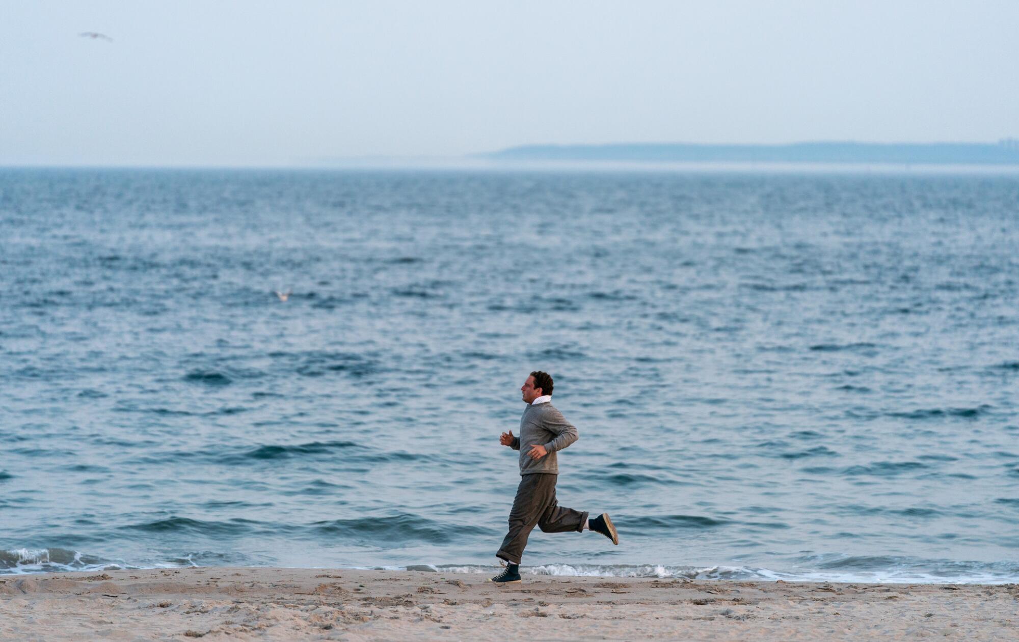 A man jogs along a beach.