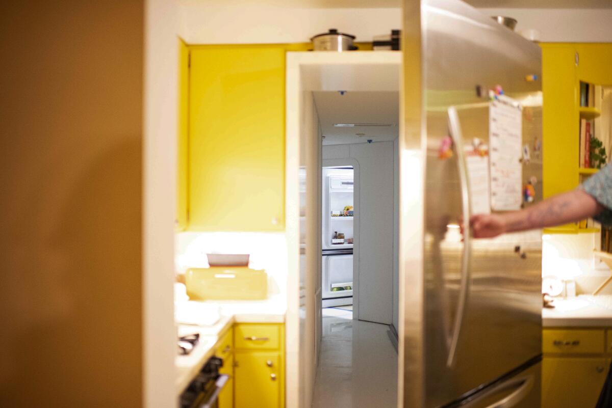 A refrigerator door opens to the next room.