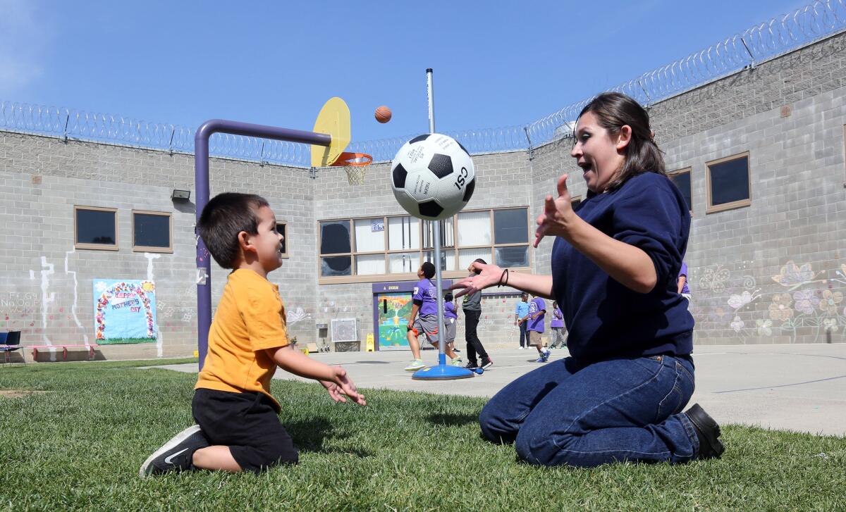 En esta foto tomada el 3 de mayo de 2014, la reclusa Erica Carmona, de 21 años, lanza un balón de fútbol de un lado a otro con su hijo, Dominic, de 3 años, durante su visita a las instalaciones para mujeres de Folsom, en Folsom, California. De las 400 mujeres encarceladas en Folsom, el 25% son latinas.