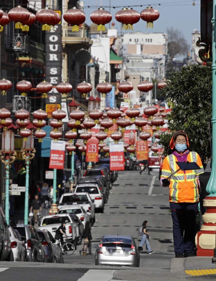 FILE - A masked worker cleans a street, Friday, Jan. 31, 2020, in the Chinatown district in San Francisco. COVID-19 case numbers are on the decrease in Los Angeles County but a top health official said Thursday, Jan. 27, 2022, it's too soon to consider relaxing mask and vaccination requirements in LA, as San Francisco plans to do next week. (AP Photo/Ben Margot, File)