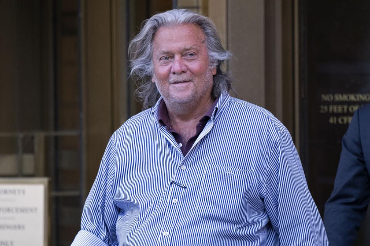 Stephen Bannon smiling as he walks out of a courthouse.