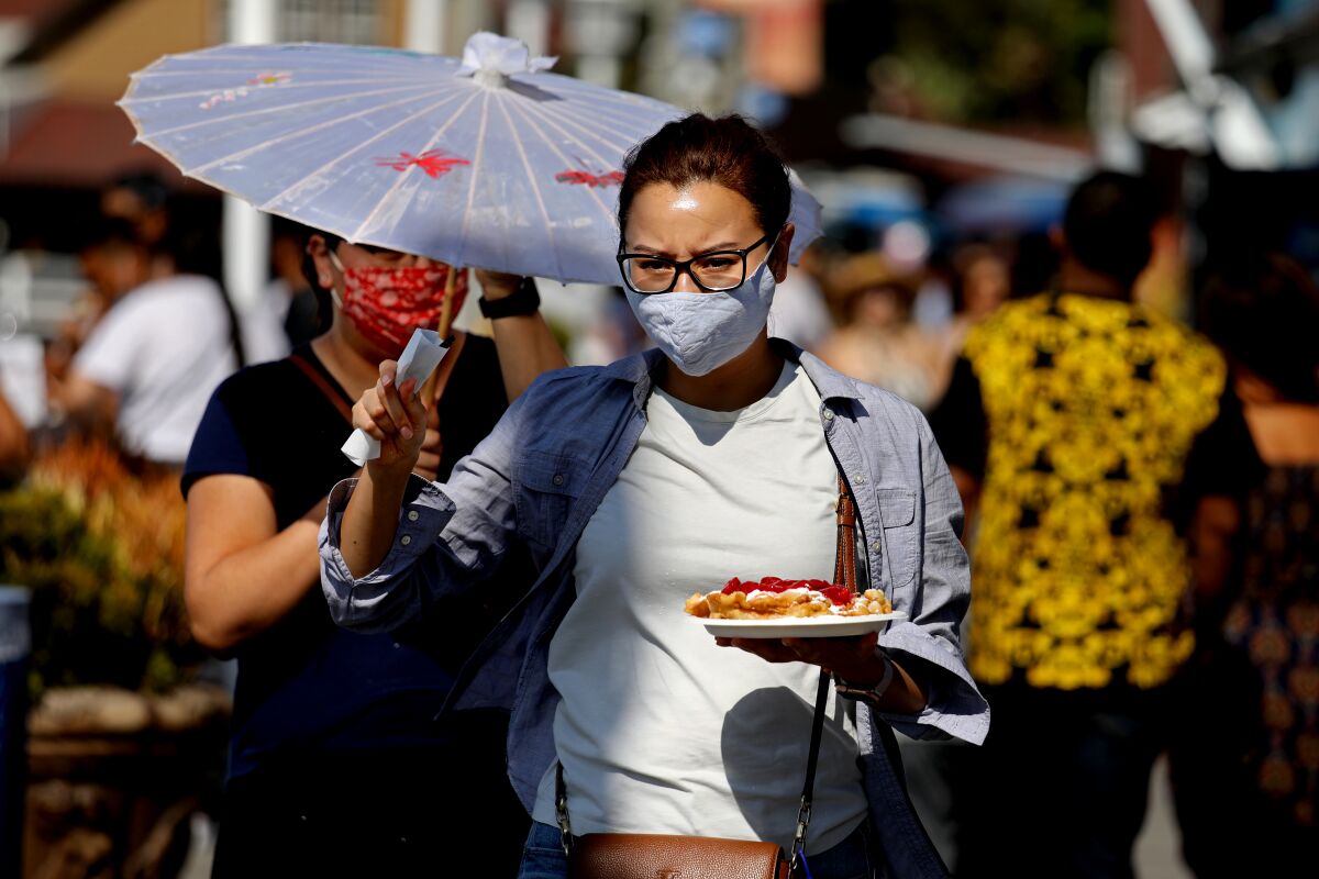 A woman wearing a mask holds a plate of food