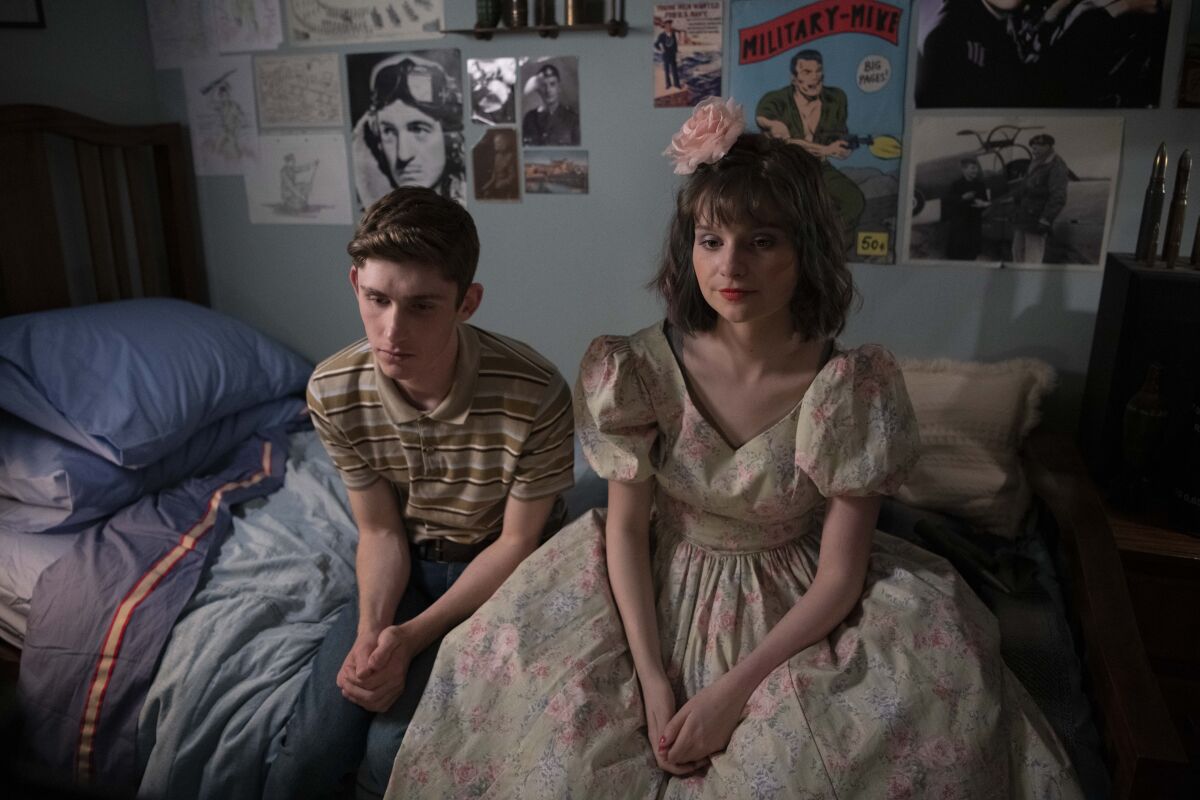 A teenage boy and girl sitting on a bed