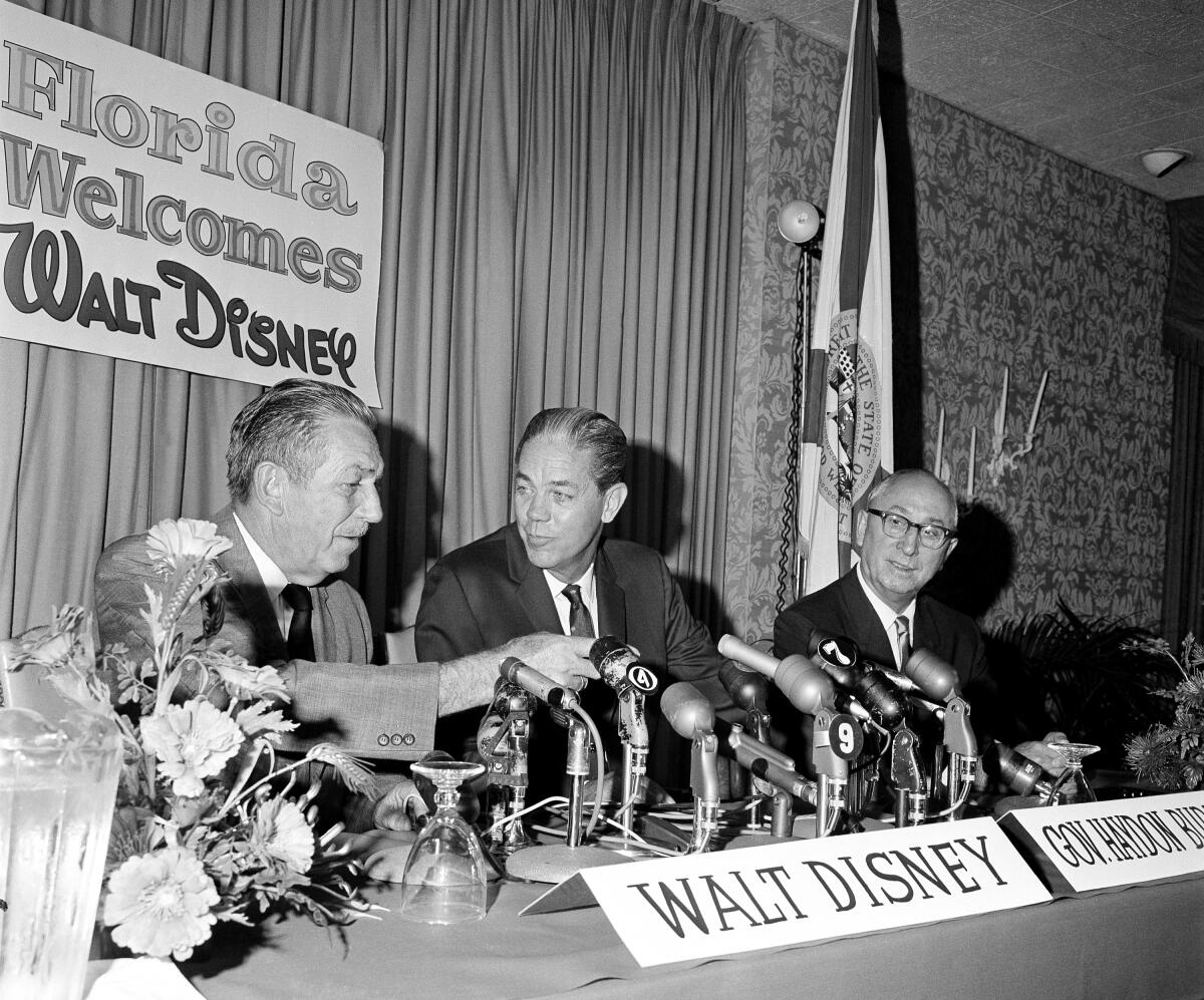 Walt Disney, left, gestures as he talks with Florida Gov. Haydon Burns in 1965. At right is Disney's brother, Roy.