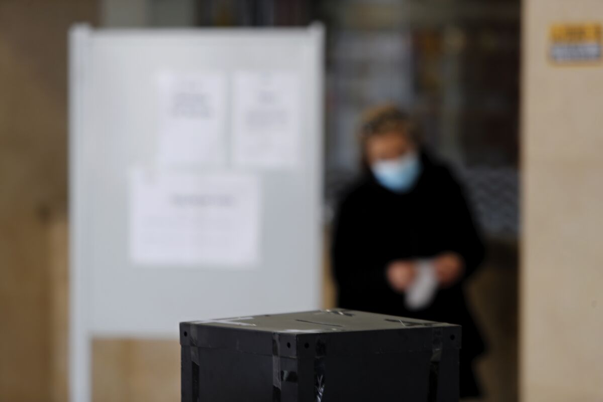 FILE - A woman wearing a face mask folds her ballot at a polling station in Lisbon, to vote in Portugal's presidential election, Jan. 24, 2021. Political leaders in Portugal said Wednesday, Jan. 5, 2022, they are trying to figure out how to hold a general election scheduled for Jan. 30 amid a surge in COVID-19 cases that is confining hundreds of thousands of potential voters to their homes. (AP Photo/Armando Franca, File)