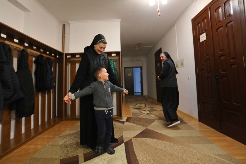 Hoshiv, Ukraine-May 1, 2022-Sister Bernadette, left, plays with Volodymyr, age 5, one of the children staying at the Sisters of the Holy Family monastery on May 1, 2022. In the foothills of the Carpathian mountains, the Sisters of the Holy Family are helping the war effort by housing misplaced people from across Ukraine. (Carolyn Cole / Los Angeles Times)