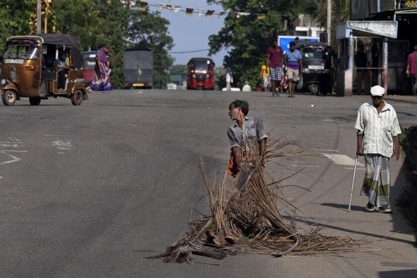A man pulls fallen coconut leaves to be used as firewood amid shortage of cooking gas along a usually congested road in Colombo, Sri Lanka, Thursday, June 23, 2022. Sri Lanka's prime minister says the island nation's debt-laden economy has "collapsed" as it runs out of money to pay for food and fuel. (AP Photo/Eranga Jayawardena)