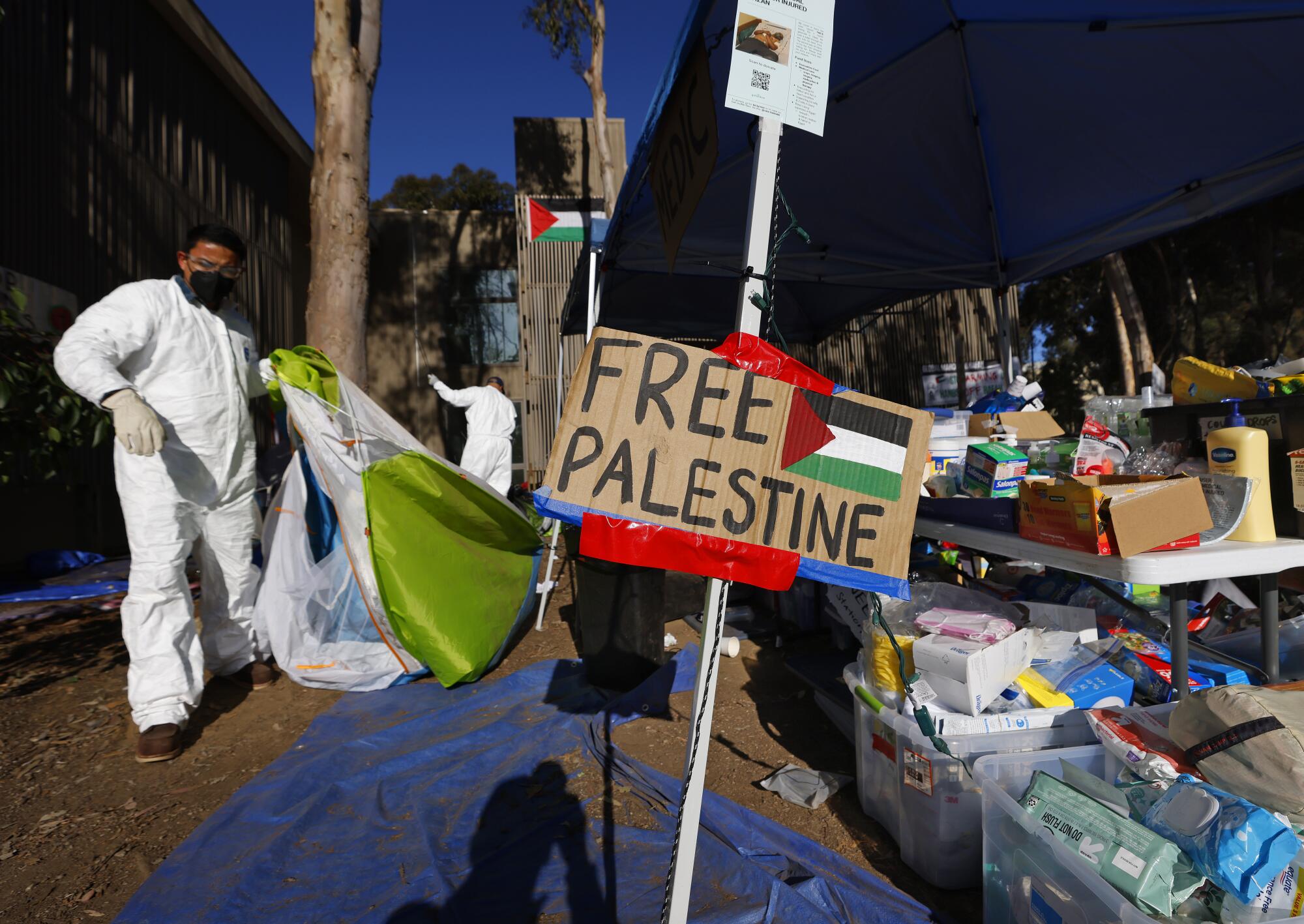 Workers clean up debris at a Free Palestine Camp along Library Walk at UC San Diego after law enforcement broke it up.