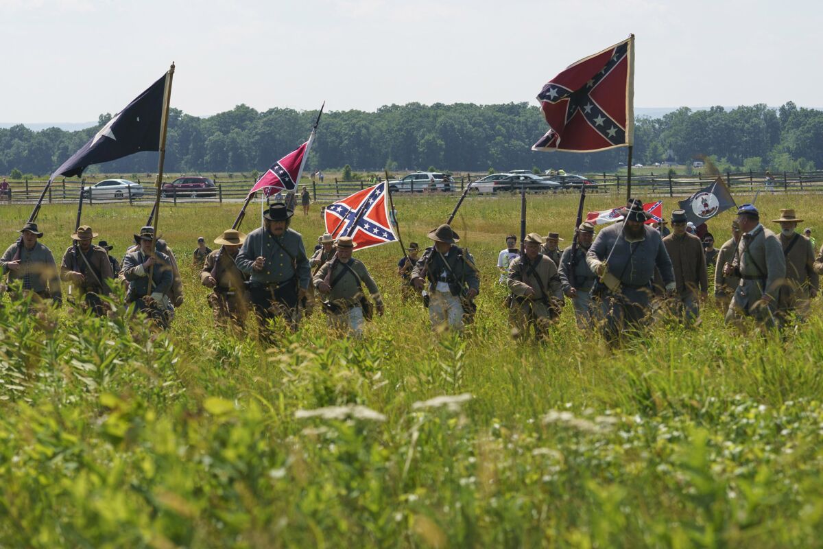 FILE - In this Friday, July 3, 2020, file photo, Civil War reenactors marching with Confederate battle flags during their reenactment of Pickett's Charge at Gettysburg National Military Park in Gettysburg, Pa. The banner, with its red field and blue X design, is the best known of the flags of the Confederacy, but the short-lived rebel nation also had other flags. (AP Photo/Carolyn Kaster, File)