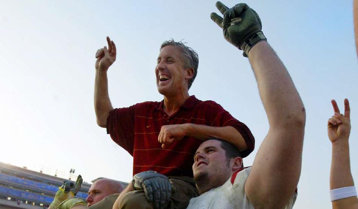 USC Coach Pete Carroll is carried off the field by Jacob Rogers, left, and Zach Wilson after USC beat UCLA 52–21 at the Rose Bowl on Nov. 23, 2002.