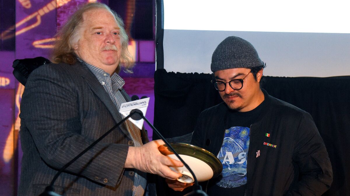 Jonathan Gold presents chef Carlos Salgado of Taco Maria with The Times' Restaurant of the Year award during this year's Food Bowl in downtown Los Angeles on April 30.