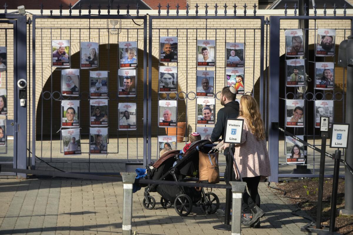 A couple with a stroller look at fliers affixed to the Israeli Embassy gates.