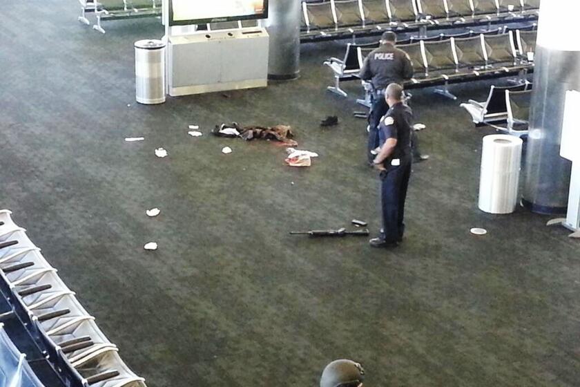 Police officers stand near an assault-style rifle in Terminal 3 of Los Angeles International Airport where a gunman opened fire on Nov. 1, killing one person and wounding three others.