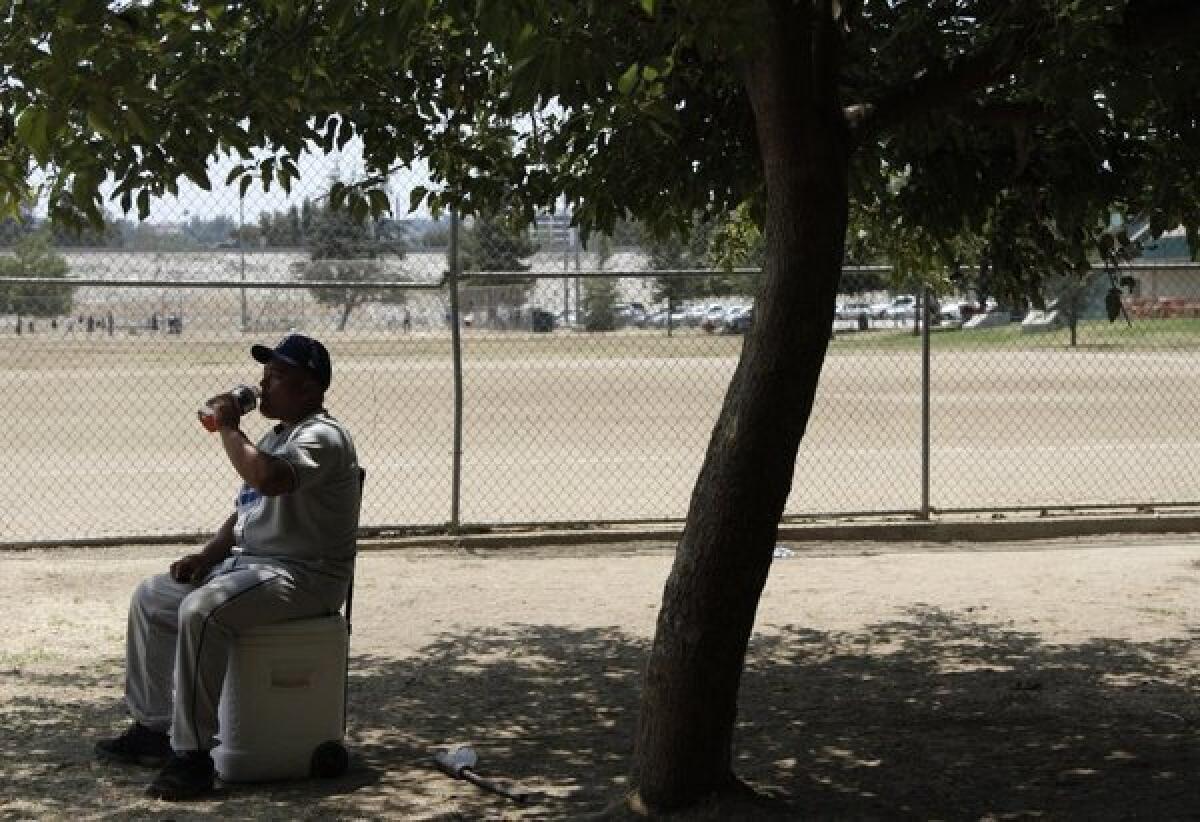 Sunday baseball league player Alex Gallegos breaks for a drink and some shade at the Sepulveda Basin Recreation Center during the weekend heat wave.